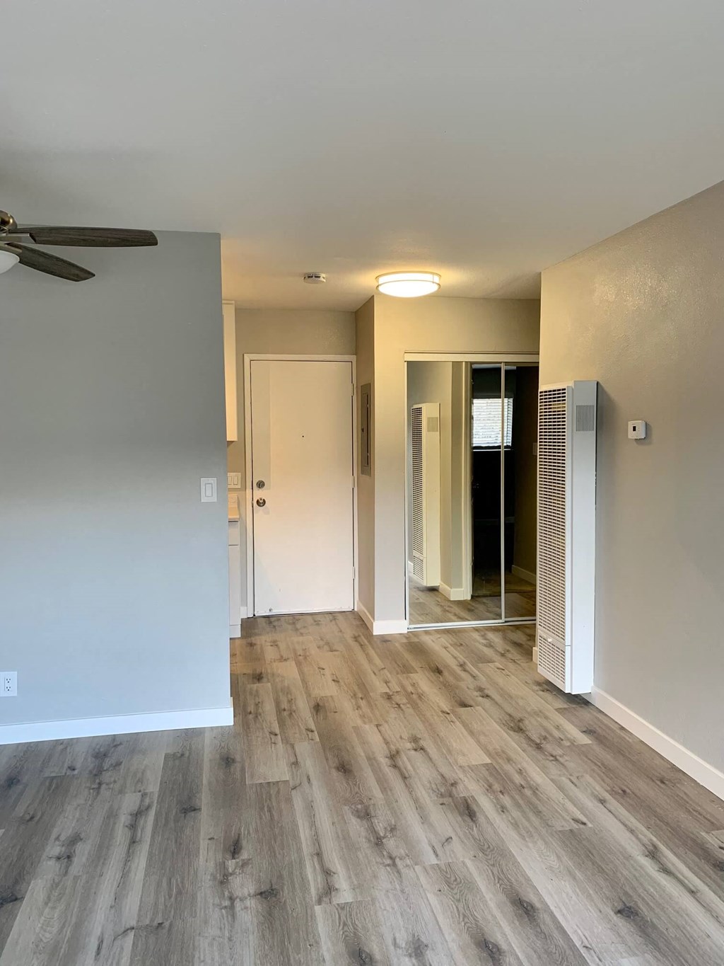 a renovated living room with wood floors and a ceiling fan