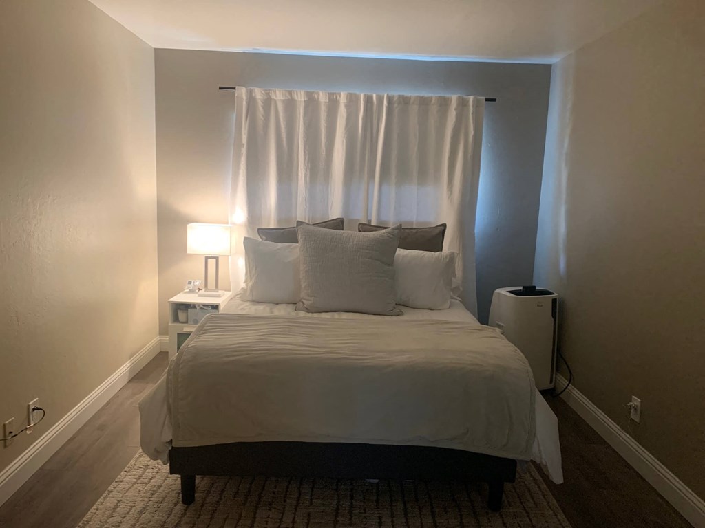 a bedroom with a bed and a window with white curtains