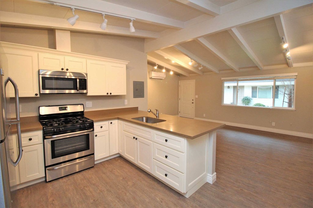 an empty kitchen with white cabinets and stainless steel appliances