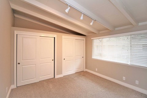 a bedroom with two closets and two doors and a window