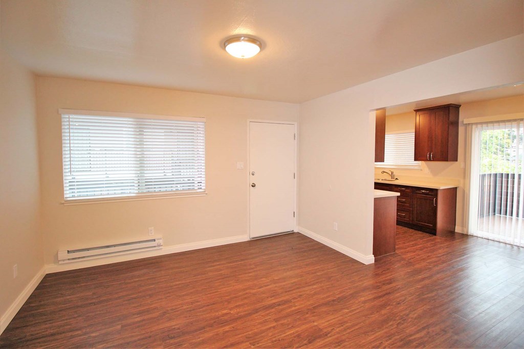 an empty living room and kitchen with wood floors and a window