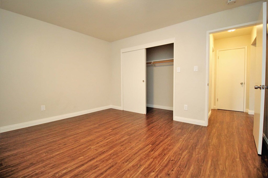 an empty living room with wood flooring and an open closet