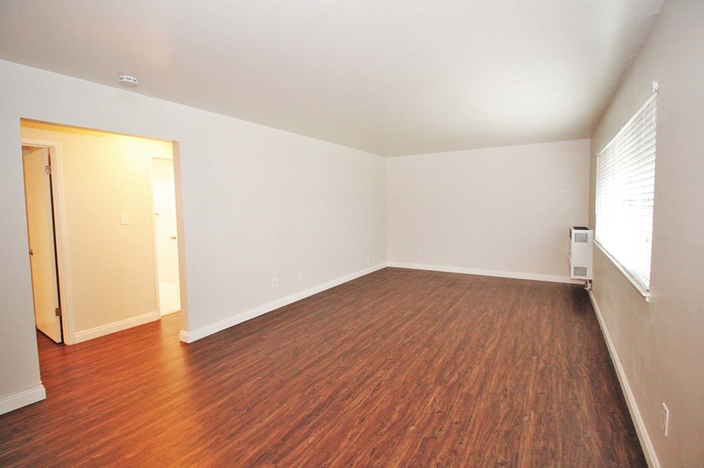 an empty living room with wood flooring and a window