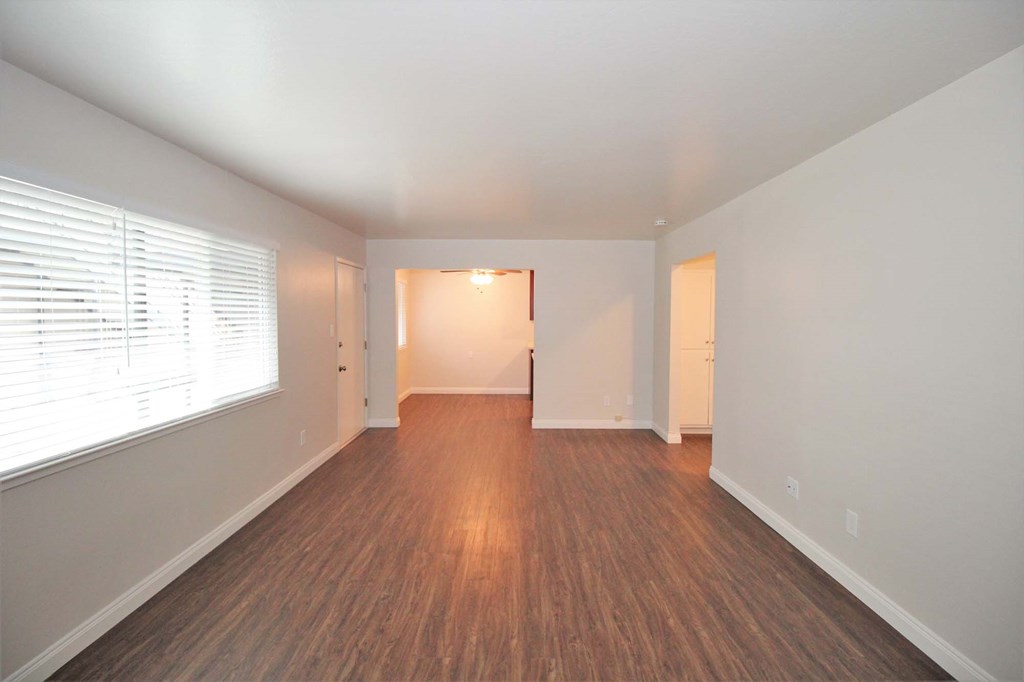 an empty living room with a large window and wood flooring