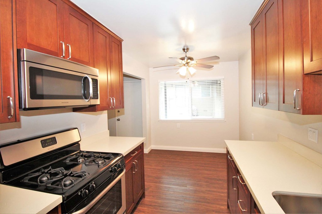 a kitchen with a stove and microwave and wooden cabinets