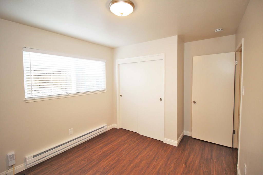 a bedroom with wood flooring and a window and a door