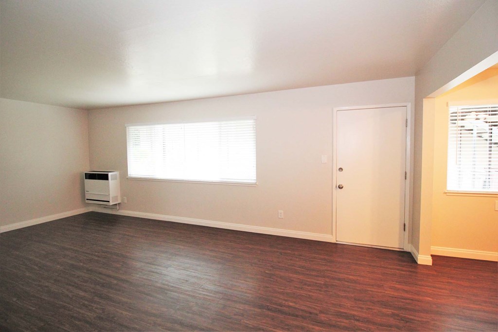 an empty living room with wood floors and a window
