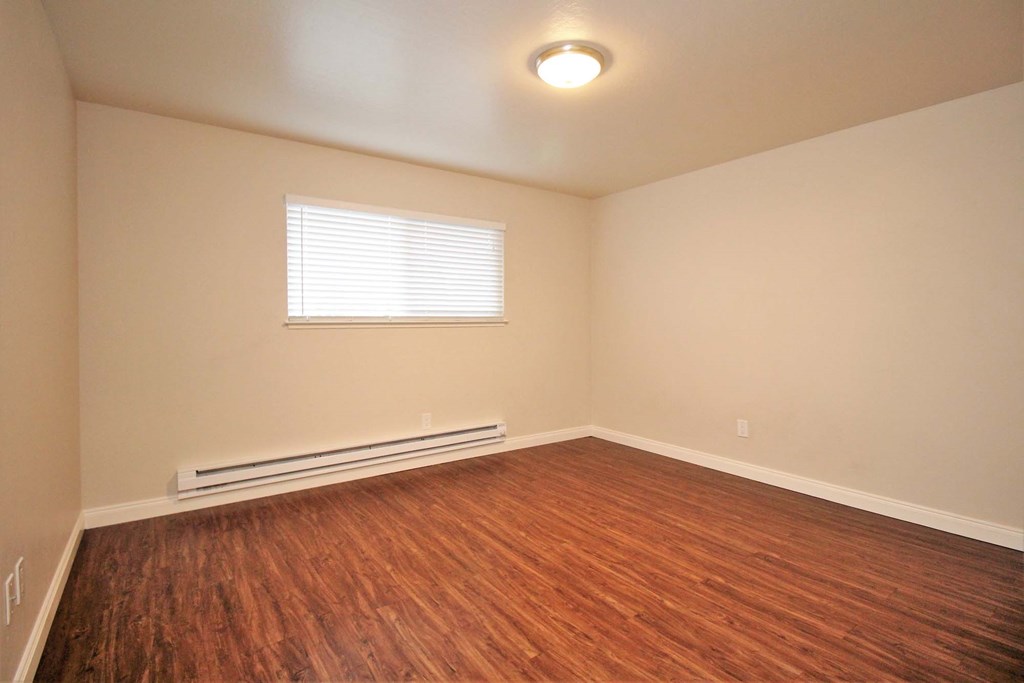 an empty living room with wood flooring and a window