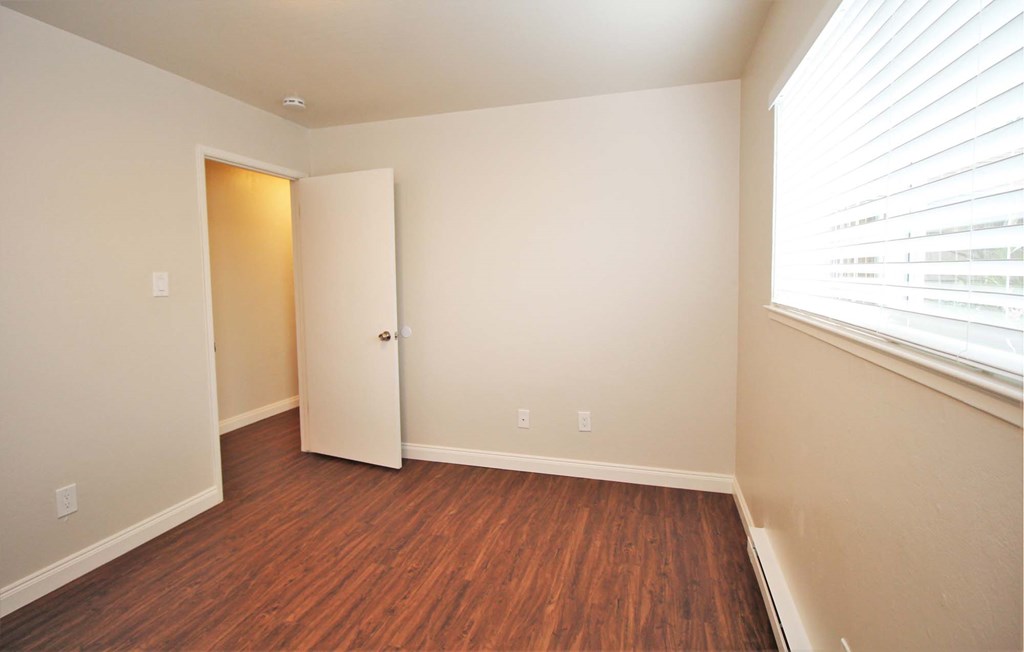 a bedroom with wood flooring and a closet