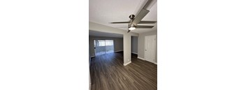 an empty living room with wood flooring and a ceiling fan