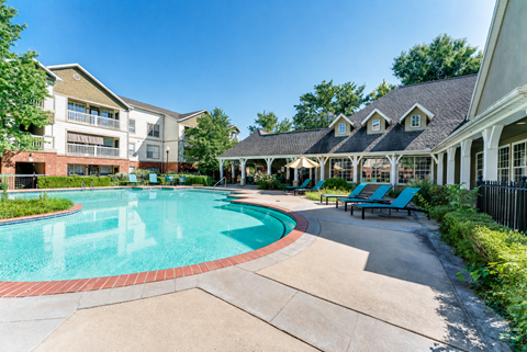 A swimming pool surrounded by a building and a gazebo.