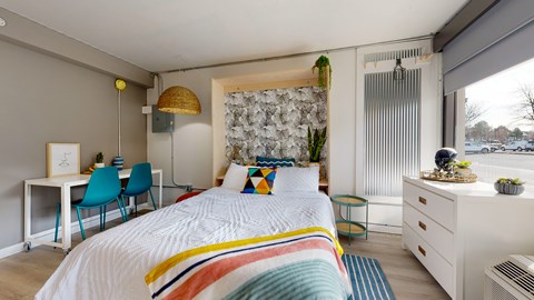 A bedroom with a bed, desk, and chair.