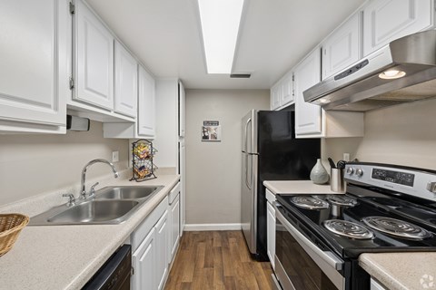 A kitchen with white cabinets and a black refrigerator.