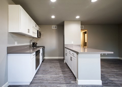 A kitchen with white cabinets and a grey counter top.