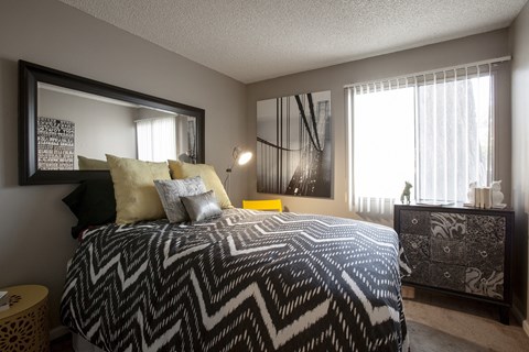 A bedroom with a patterned bedspread and a large mirror on the wall.