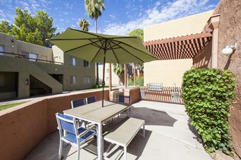 A patio with a table and chairs under a green umbrella.