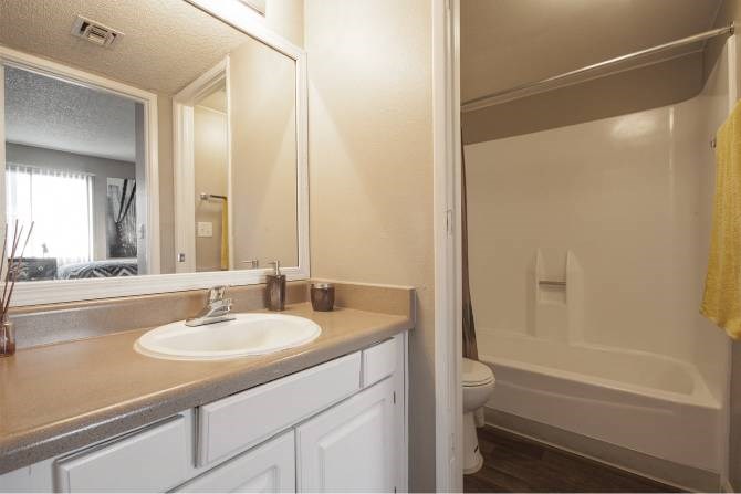 A bathroom with a sink, mirror, and bathtub.