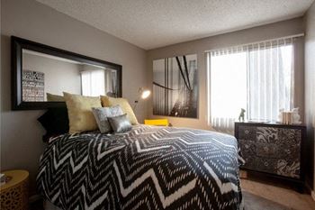 A bedroom with a patterned bedspread and a large mirror on the wall.
