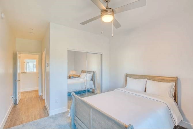 A bedroom with a bed, a ceiling fan, and a mirror.