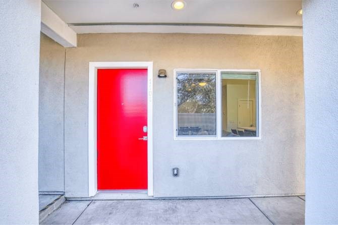 A red door is on the left side of a white wall.