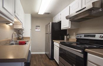 A kitchen with a black refrigerator and stove top oven.