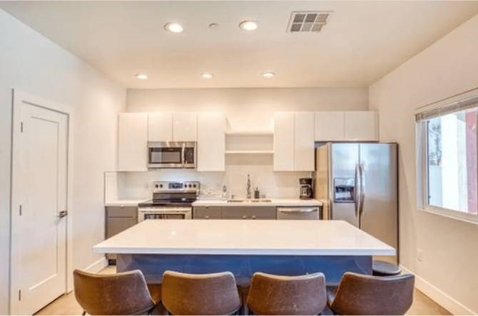 A modern kitchen with a large island and chairs.