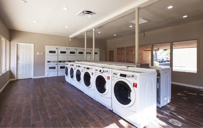 A laundry room with a row of washing machines.