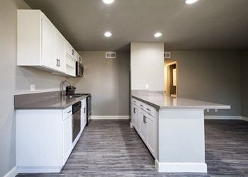 A kitchen with white cabinets and a grey countertop.