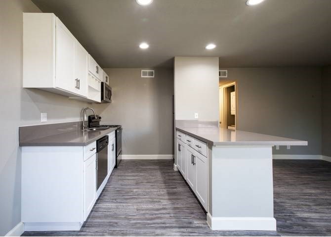 A kitchen with white cabinets and a grey countertop.
