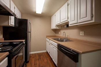 A kitchen with a black stove top oven and black dishwasher.