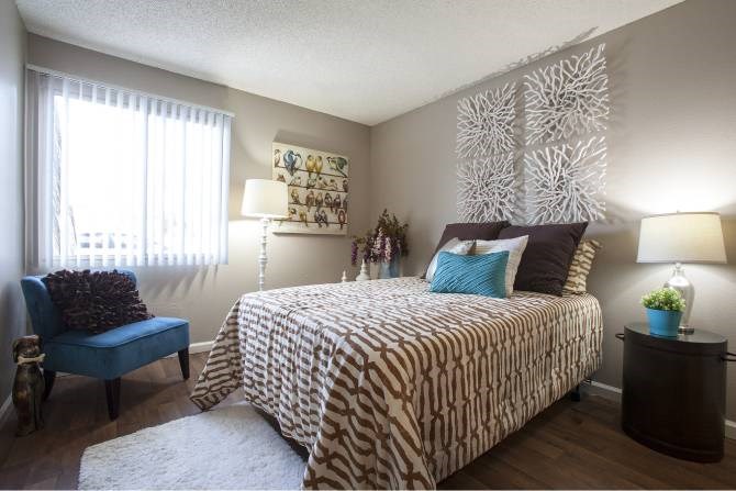 A bedroom with a patterned bedspread and a blue chair.