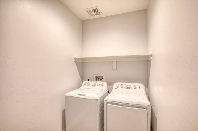 Two white washing machines in a small laundry room.