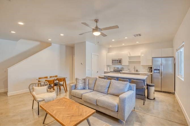A spacious living room with a couch, chairs, and a dining table.