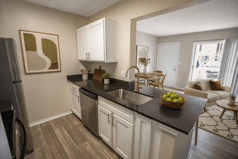 A kitchen with white cabinets and a black countertop.