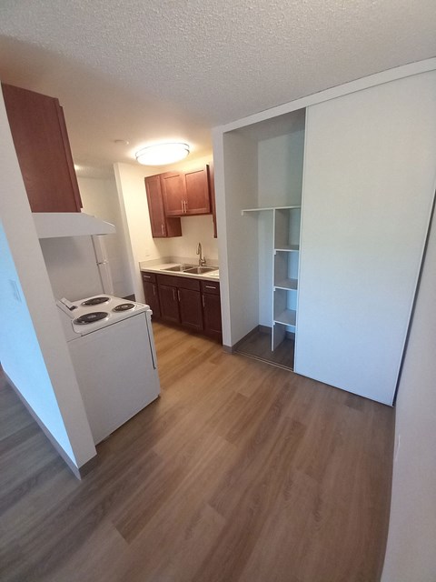 A small kitchen with a stove top oven and wooden floors.