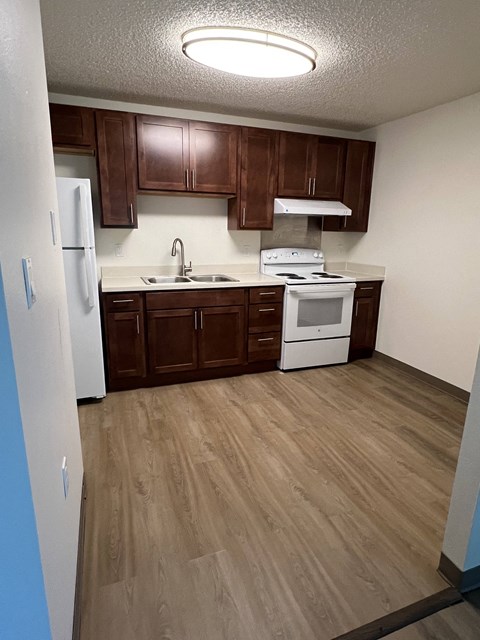 A kitchen with brown cabinets and a white fridge.