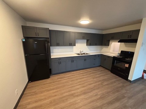 A kitchen with black appliances and wooden floors.