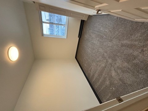 A small room with a window and a light on the wall.
