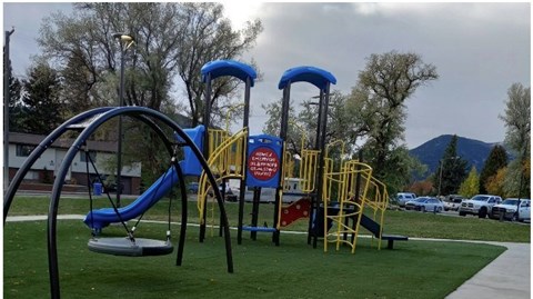 A playground with a blue slide and yellow equipment.