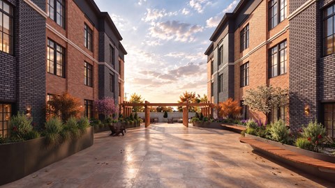 A sunset view of a brick building with a walkway in front.