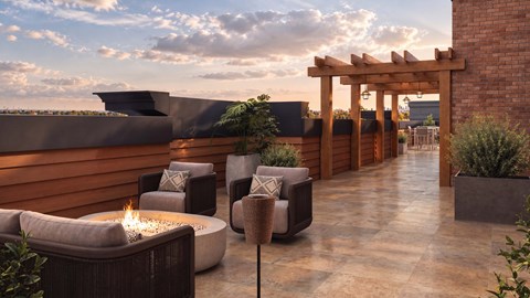 A patio with a fire pit and chairs.