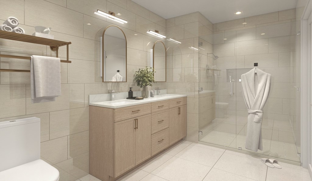 A bathroom with a white toilet, a sink with a plant on it, and a mannequin in the shower.