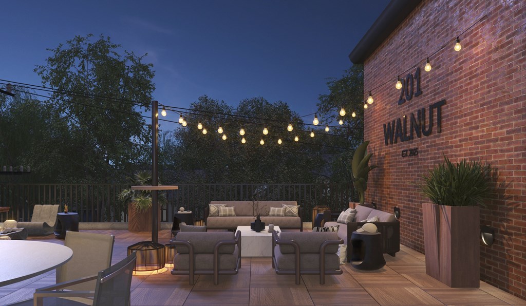 A patio area with tables and chairs is illuminated by string lights.