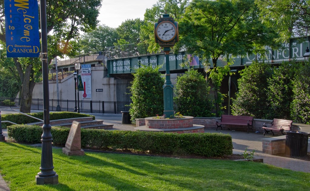 A park with a bench, a clock and a sign that says Cranford.