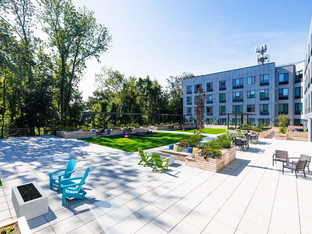 an outdoor patio with blue chairs and a lawn in front of a building