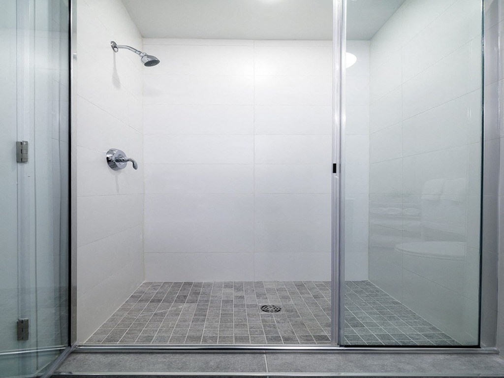 a glass shower stall in a white tiled bathroom