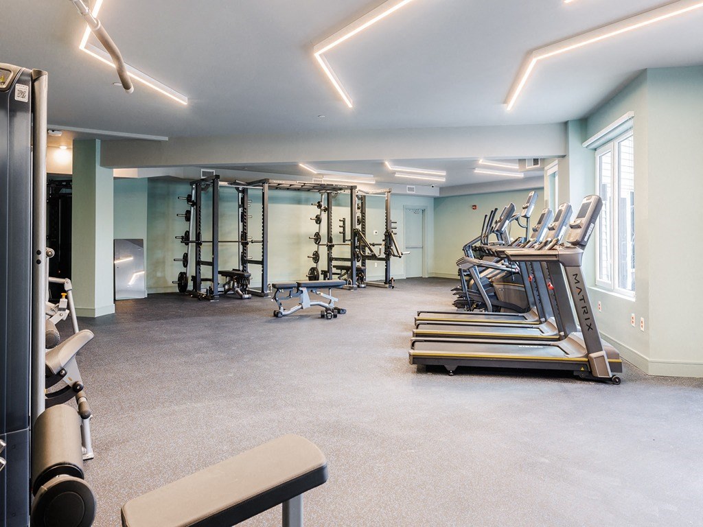 a gym with treadmills and other exercise equipment in a room with windows