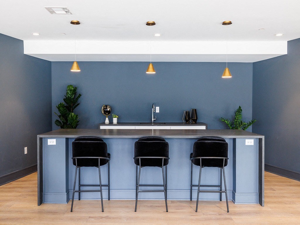 a kitchen with blue walls and a counter with three stools