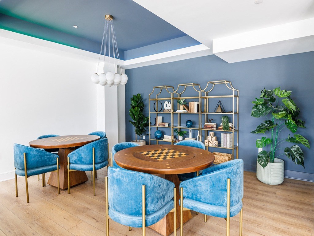 a dining room with blue chairs and a table with a chess board