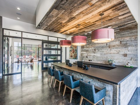 A modern kitchen with a wooden ceiling and a long island with chairs.at Infinity on Yorktown, Dallas, TX